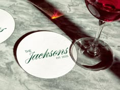 two wine glasses sitting next to each other on top of a table with coasters