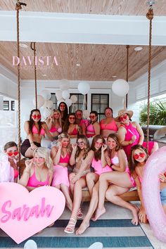 a group of women in pink bathing suits posing for a photo on a porch swing