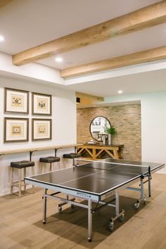 a ping pong table in the middle of a room with chairs and pictures on the wall