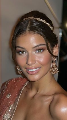 a woman in a pink dress with gold jewelry on her head and one eye open