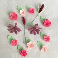 paper flowers arranged in a circle on a white surface with green leaves and pink flowers