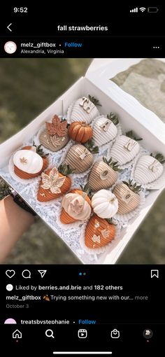 someone holding a box filled with pumpkins on top of a table