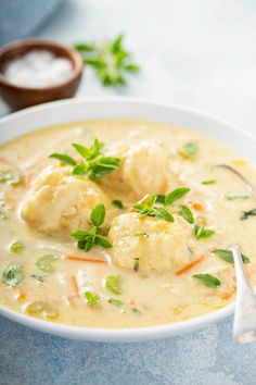 a white bowl filled with soup and dumplings on top of a blue tablecloth