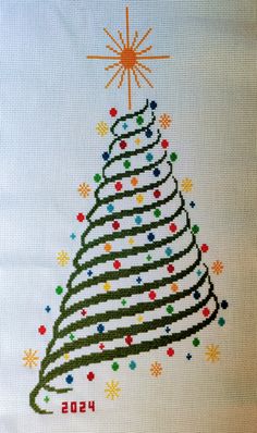 a cross stitch christmas tree with stars and snowflakes on the top is shown