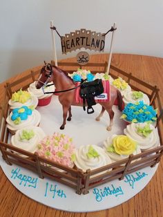 a birthday cake decorated with cupcakes and a horse