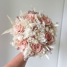 a bridal bouquet with pink roses and white baby's breath in someones hand