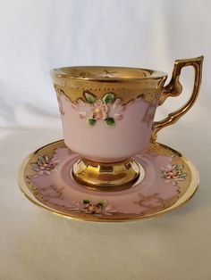 a pink cup and saucer with gold trim