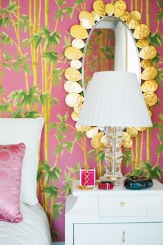 a bedroom with pink wallpaper and gold palm trees on the wall next to a white bed