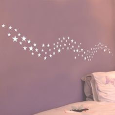 a bed room with a neatly made bed and stars on the wall