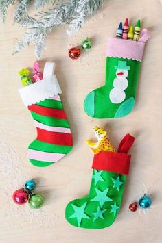 three christmas stockings are on the table with crayons and colored pencils next to them