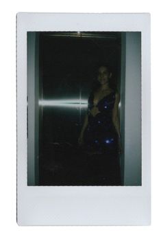 a woman in a blue dress is standing by an elevator door and looking at the camera