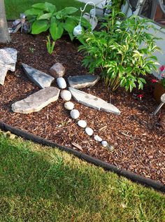 a garden with rocks and stones arranged in the shape of a cross on top of mulch