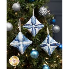 three blue and white ornaments hanging from a christmas tree