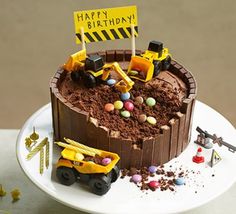 a birthday cake with construction vehicles and dirt on the top is sitting on a white plate