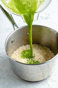 green liquid being poured into a pot filled with white rice