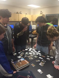 a group of young men standing around a table with cell phones and cards on it