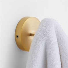 a towel is hanging on the wall next to a gold robe rack and white towels