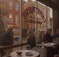 people sitting at tables in front of a window with the words cafe tristee on it