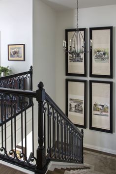 a staircase with pictures on the wall and chandelier hanging from it's handrail