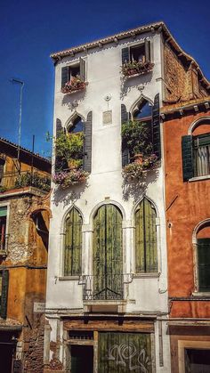 an old building with green shutters and flower boxes on the windows in venice, italy