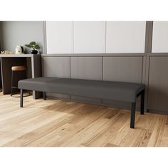 a black bench sitting on top of a hard wood floor next to a white cabinet