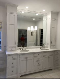 a large bathroom with double sinks and mirrors on the wall, along with white cabinets