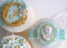 three decorated cookies sitting on top of white doily with blue and gold trimmings