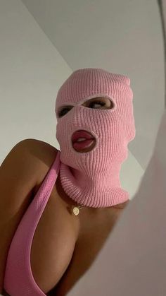 a woman wearing a pink mask with her tongue sticking out and looking at herself in the mirror