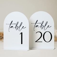 two white table numbers with black ink on them