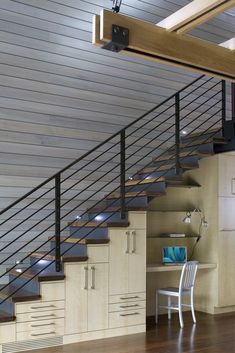 a room that has some stairs and cabinets on the wall next to it, with a desk in front of it