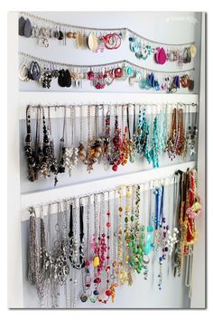 a white wall filled with lots of necklaces and bracelets hanging from it's sides