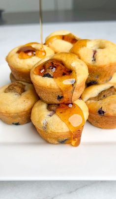 blueberry muffins are being drizzled with honey on a white plate