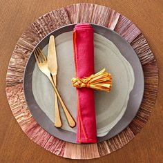 a silver plate topped with a red napkin and gold fork