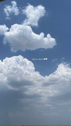 an airplane is flying in the blue sky with white clouds and some buildings below it