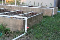 several raised wooden planters with plants growing in them on the grass near a building