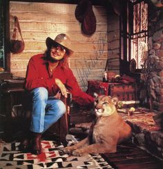 a man sitting in a chair next to a cougat and a dog on a rug