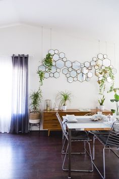 an instagram photo of a dining room table and chairs with plants on the wall