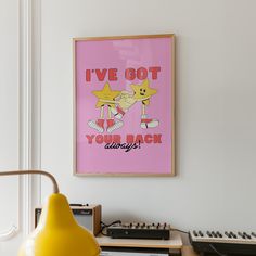 a pink poster hanging on the wall next to a yellow lamp and record player's equipment