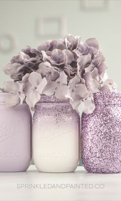 three mason jars with flowers in them are sitting on a table next to each other