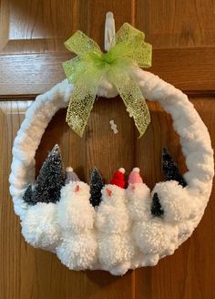 a white wreath with black and white pom poms hanging from it's side