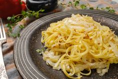 a plate with some noodles on it next to a fork and knife