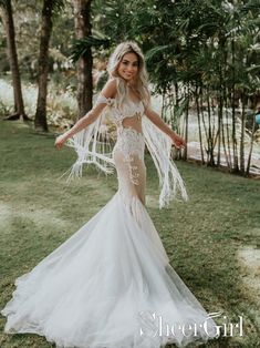 a woman in a wedding dress standing on grass with her arms out and hands behind her back