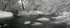 a river surrounded by snow covered trees and rocks