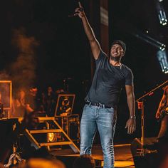 a man standing on top of a stage with his arms in the air and people around him