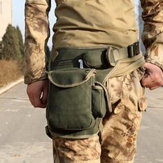 a man in camo pants holding his skateboard on the street while wearing an army uniform