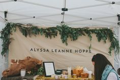 a woman standing in front of a table with food on it and greenery hanging from the ceiling