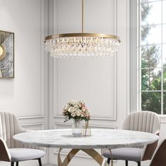 a dining room table with chairs and a chandelier hanging from the ceiling above it