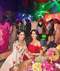 two women standing next to each other in front of a table with flowers and candles