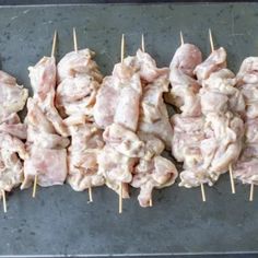 several skewers of meat on toothpicks lined up on a baking sheet