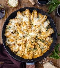 a skillet filled with cheese and sauce on top of a wooden table